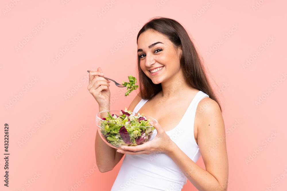 Young caucasian woman holding a salad isolated on pink background Young caucasian woman holding a salad isolated on pink background
