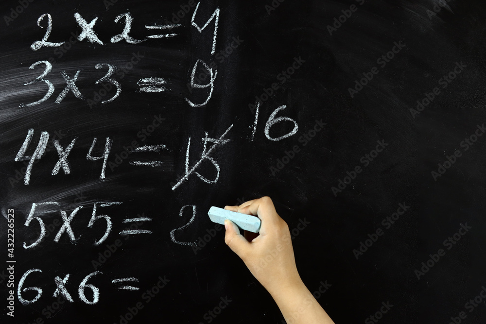 child solves mathematical examples on the school blackboard