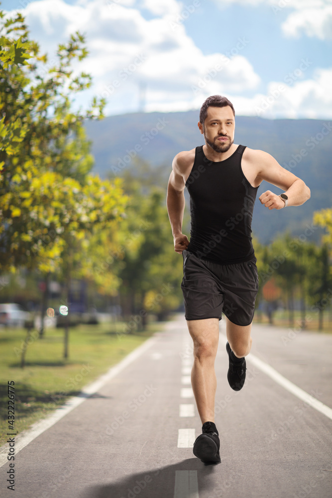 Fit man with a smartwatch jogging on a running lane