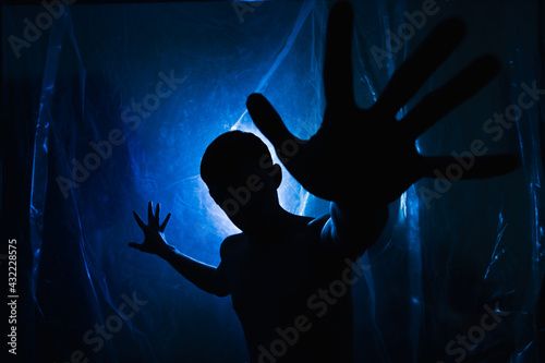 A man in the dark in a blue light. Silhouette of a man in the dark.