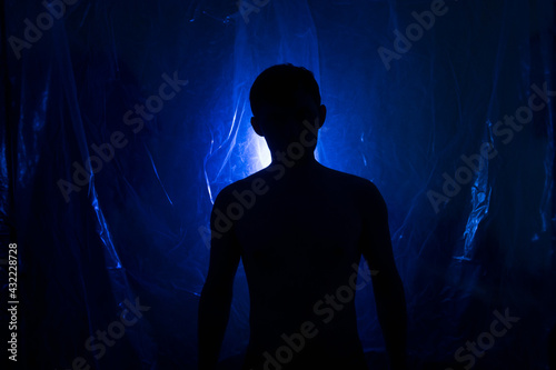 A man in the dark in a blue light. Silhouette of a man in the dark.