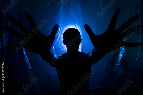 A man in the dark in a blue light. Silhouette of a man in the dark.