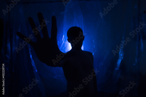 A man in the dark in a blue light. Silhouette of a man in the dark.