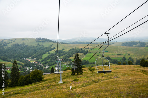 Summer cloudy landscape with empty ski lift on the green grassy hill in the Carpathian mountains, Ukraine 