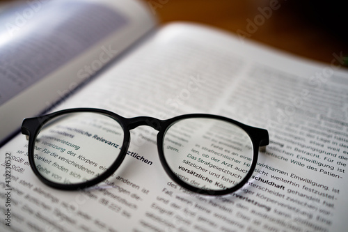 Black framed reading  glasses  on the book  close up