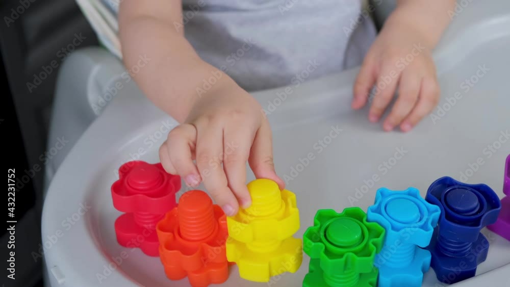 Child 2 y.o. plays with plastic colored shaped large screws and nuts, learning through the game. Child 2 y.o. plays with plastic colored shaped large screws and nuts, learning through the game.