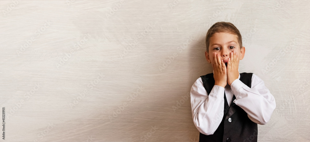 Pensive boy in school uniform goes to school for the first time. Schoolboy indoors on a light background. Free background ready for your lettering. Natural emotions. Pensive boy in school uniform goes to school for the first time. Schoolboy indoors on a light background. Free background ready for your lettering. Natural emotions.
