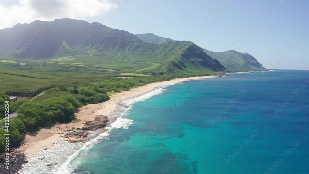 Aerial shot on the beach of Oahu Hawaii. Dream trip to green island. Outdoor adventure travel to beautiful Hawaii beach. Cinematic wild nature. Slow motion waves of transparent green sea waters.