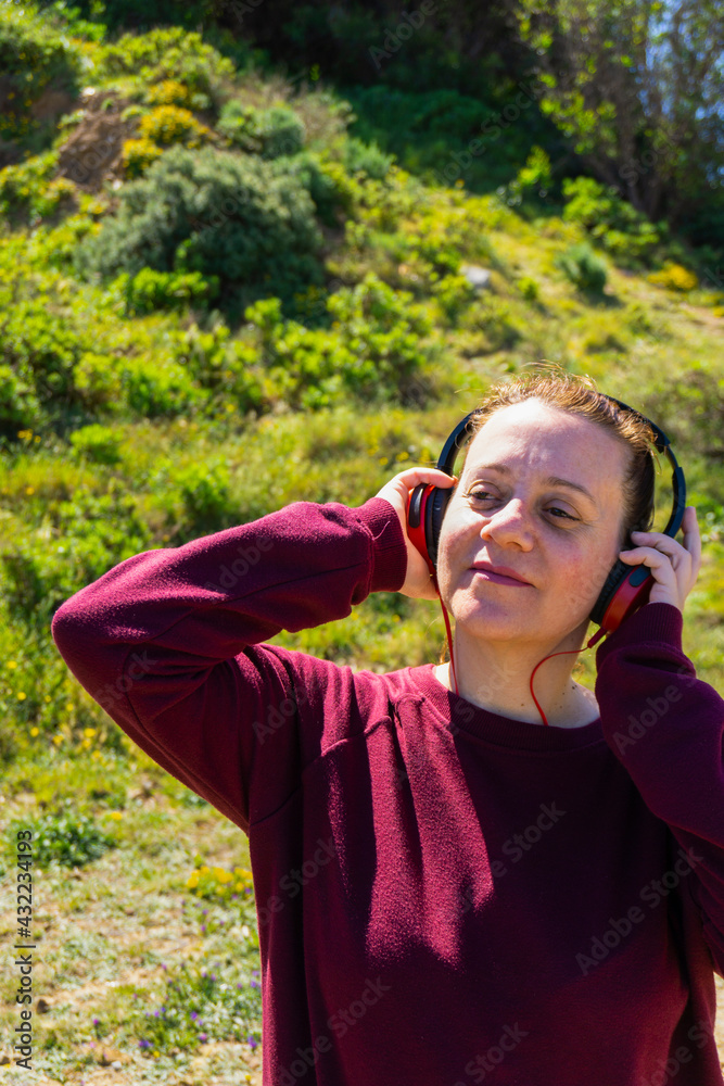 Mujer joven con auriculares escuchando musica y bailando en el parque Mujer joven con auriculares escuchando musica y bailando en el parque
