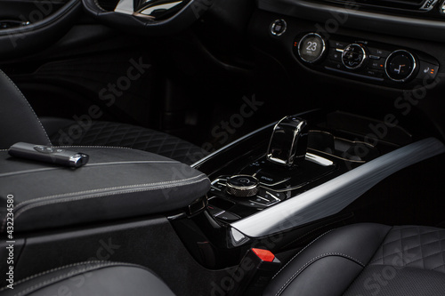 Black interior of a modern car. Focused on hift lever and dashboard. Black leather interior.