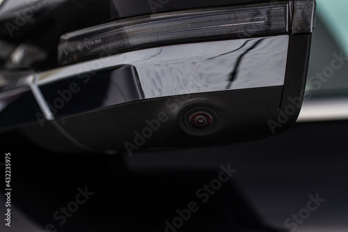 Close up view of surround view camera system on modern car side rear mirror. Blind spot and parking assistant camera.