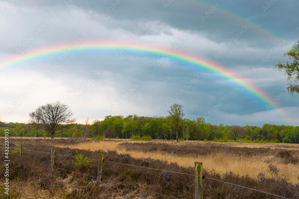 Rainbow over stormy sky. Rural landscape with rainbow over dark stormy sky in a countryside on a springtime day Rainbow over stormy sky. Rural landscape with rainbow over dark stormy sky in a countryside on a springtime day