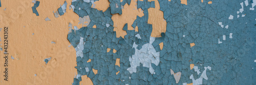 Peeling paint on the wall. Panorama of a concrete wall with old cracked flaking paint. Weathered rough painted surface with patterns of cracks and peeling. Wide panoramic grunge texture for background