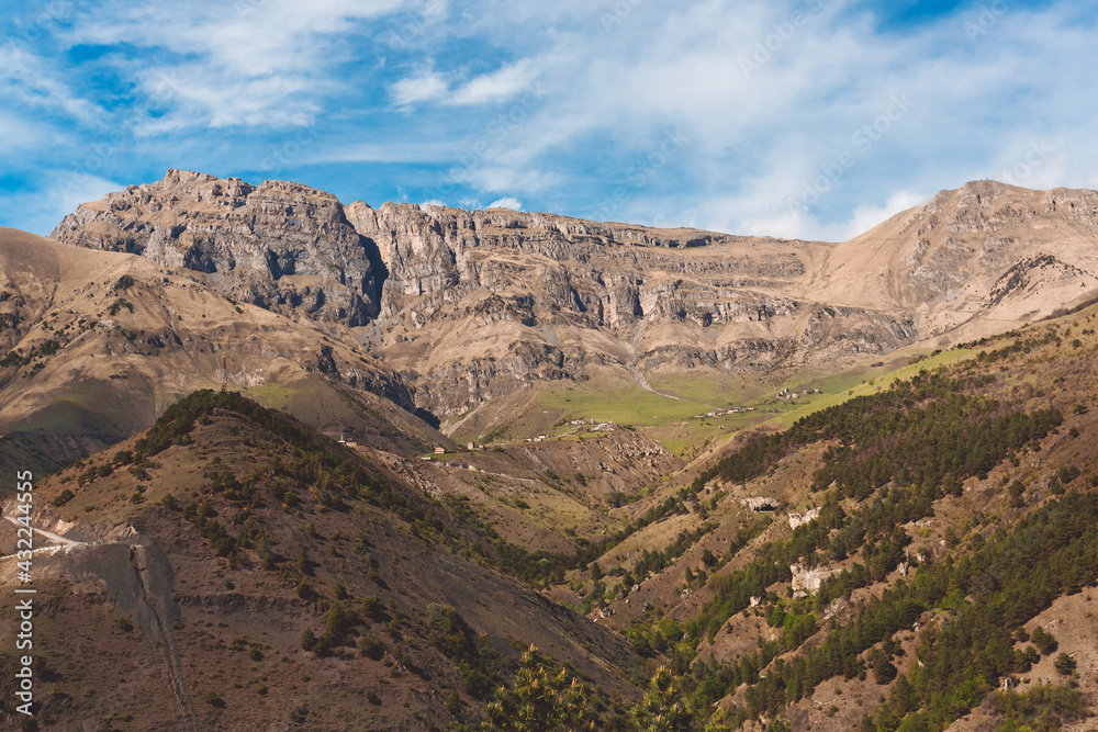 Panoramic view of Table Mountain and the village of Beyni in Ingushetia, Russia. Mountain landscape, rocks, plateau and blue sky. The road to the top. Mountain climbing. Tourist adventure.