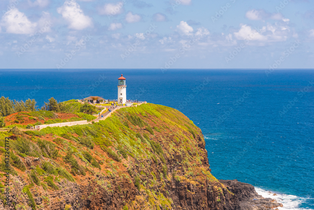Lighthouse on tropical coast with tourists and blue ocean