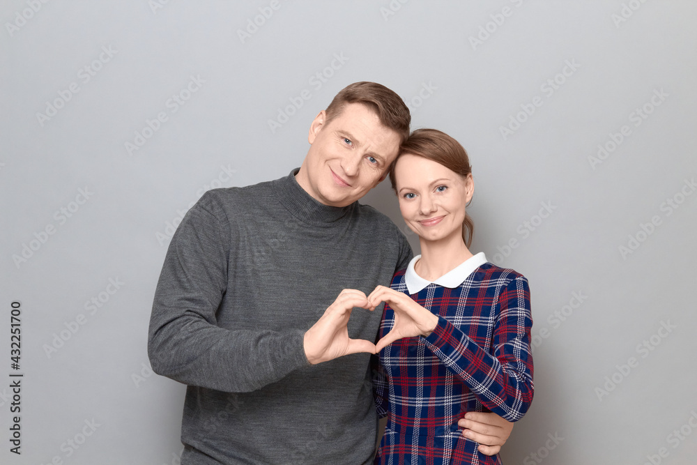 Portrait of happy couple making heart gesture with fingers and smiling Portrait of happy couple making heart gesture with fingers and smiling