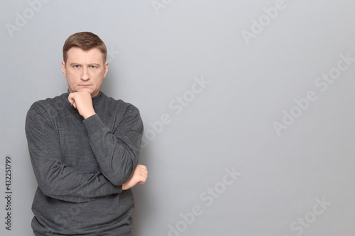 Portrait of serious man propping head with one hand, touching chin