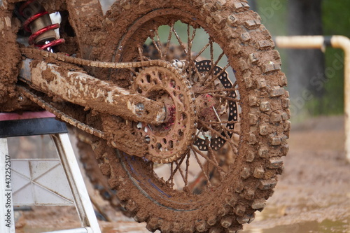 泥だらけのモトクロス用ブロックタイヤ（リア）/The motocross bike covered in mud after race in rain day.