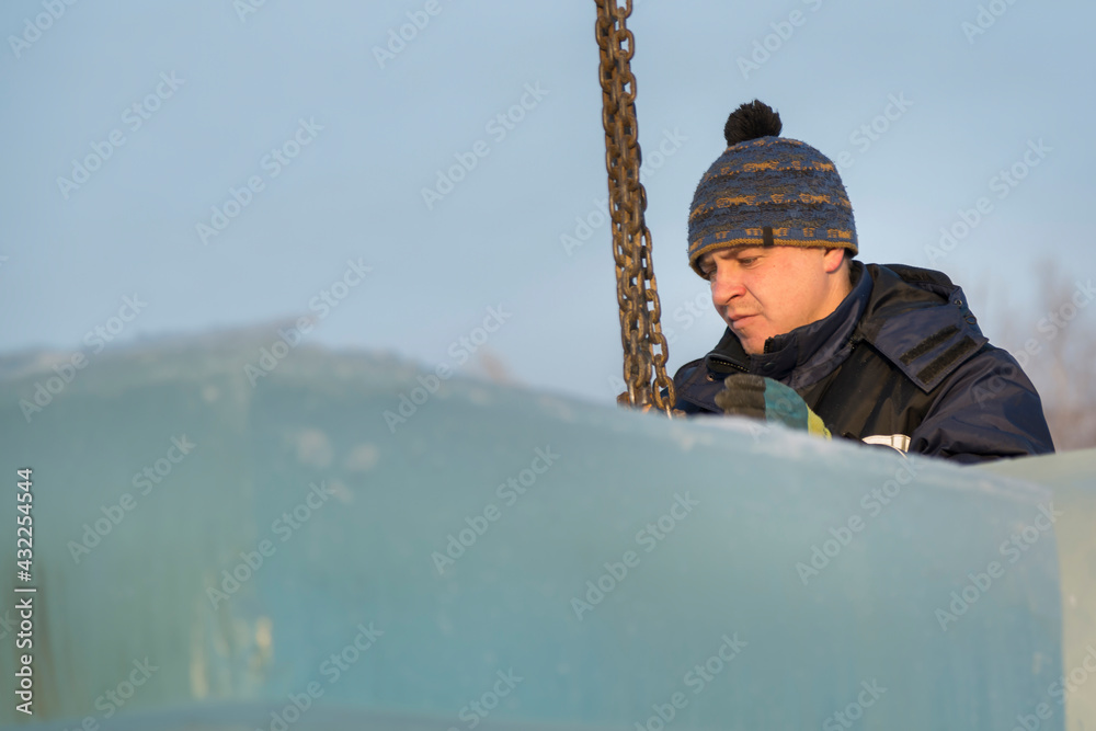 Fitter in a blue jacket works with a chain metal sling Fitter in a blue jacket works with a chain metal sling