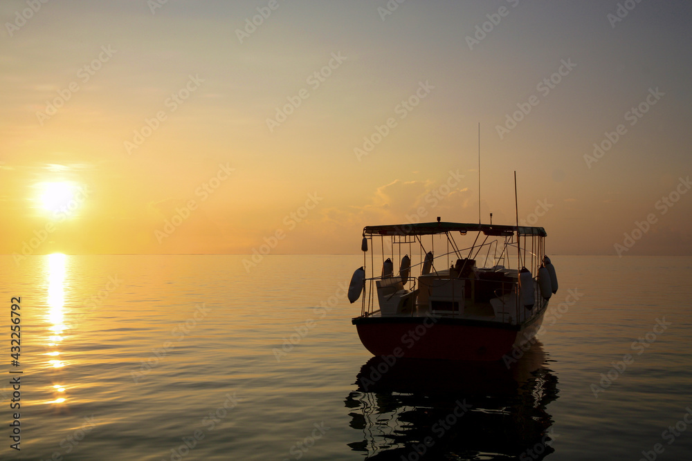 Sunrise on small passengers ship anchored at the harbor of Embudu Island, Maldives Island.
