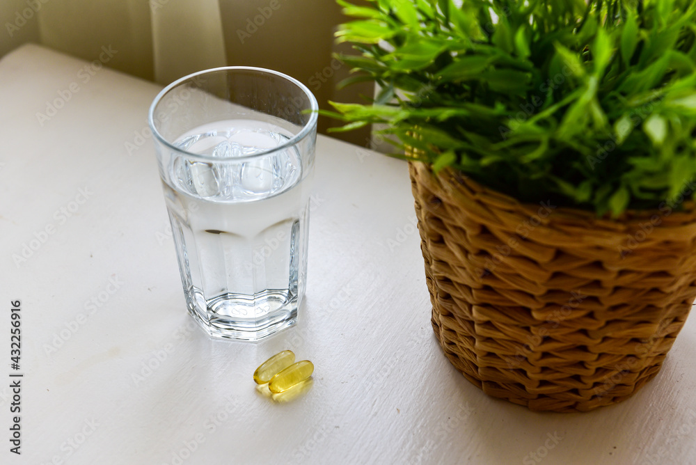 Omega-3, spirulina, chlorophyll capsules and glass of water on white wooden table. Dietary supplements, biologically active additives. vitamin pills. Health support Omega-3, spirulina, chlorophyll capsules and glass of water on white wooden table. Dietary supplements, biologically active additives. vitamin pills. Health support