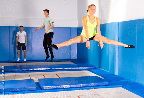 Group of active friends practicing and jumping in trampoline center © JackF