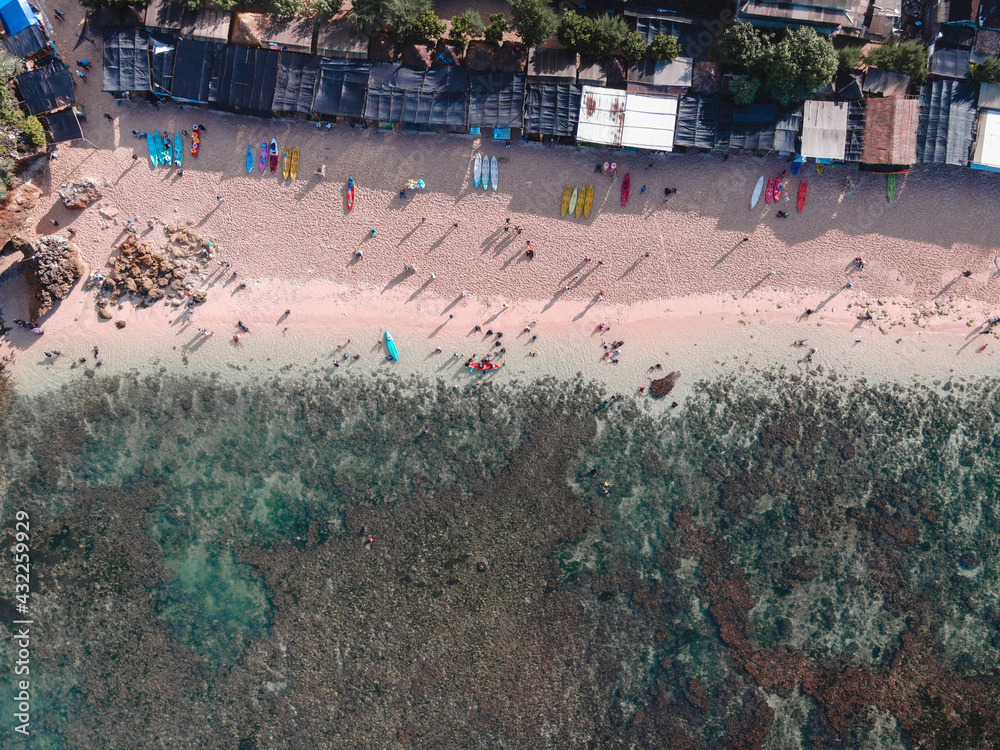Aerial drone view of Holiday In Gunung Kidul Beach, Indonesia with ocean, boats, beach, and people.