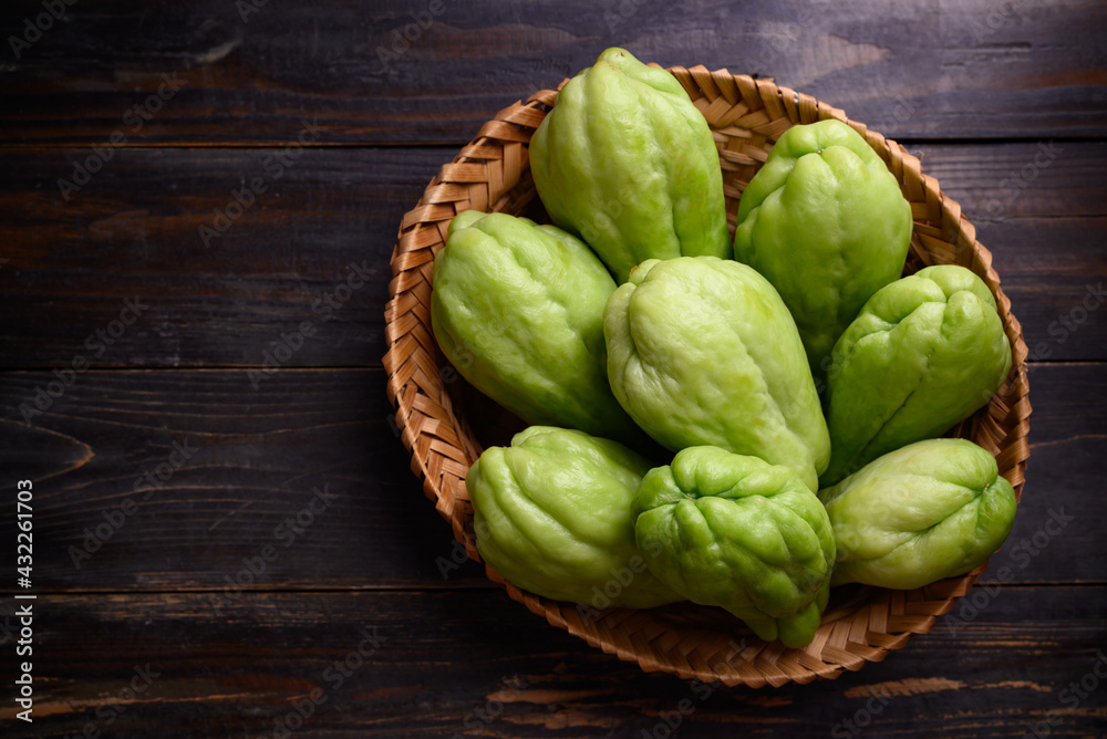 Chayote squash fruit (Mirliton, pipinola or choko) in a basket on wooden background, Edible fruit eaten both cooked and raw such as salad or salsa Chayote squash fruit (Mirliton, pipinola or choko) in a basket on wooden background, Edible fruit eaten both cooked and raw such as salad or salsa