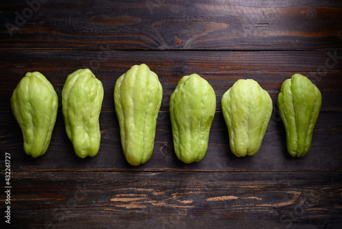 Chayote squash fruit (Mirliton, pipinola or choko) on wooden background, Edible fruit eaten both cooked and raw such as salad or salsa photo