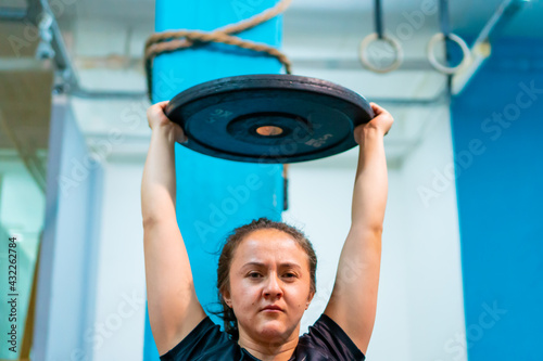 dwarf latina woman, achondroplasia, in the gym doing sit ups with barbell for abdominal muscles or hard abs, horizontal picture photo