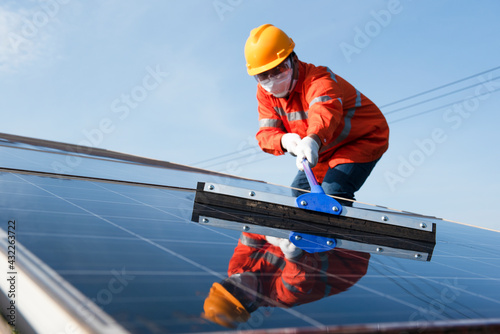 Asian technicians cleaning solar panels, technicians wearing masks to protect against germs. © somchai20162516