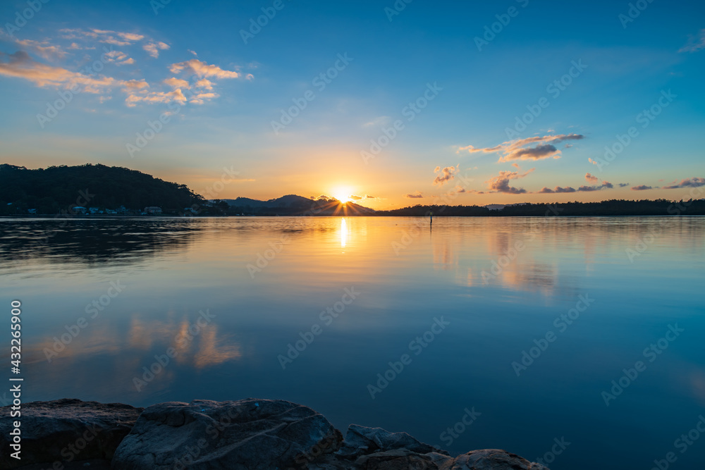 Fototapeta premium Sunrise waterscape with scattered clouds