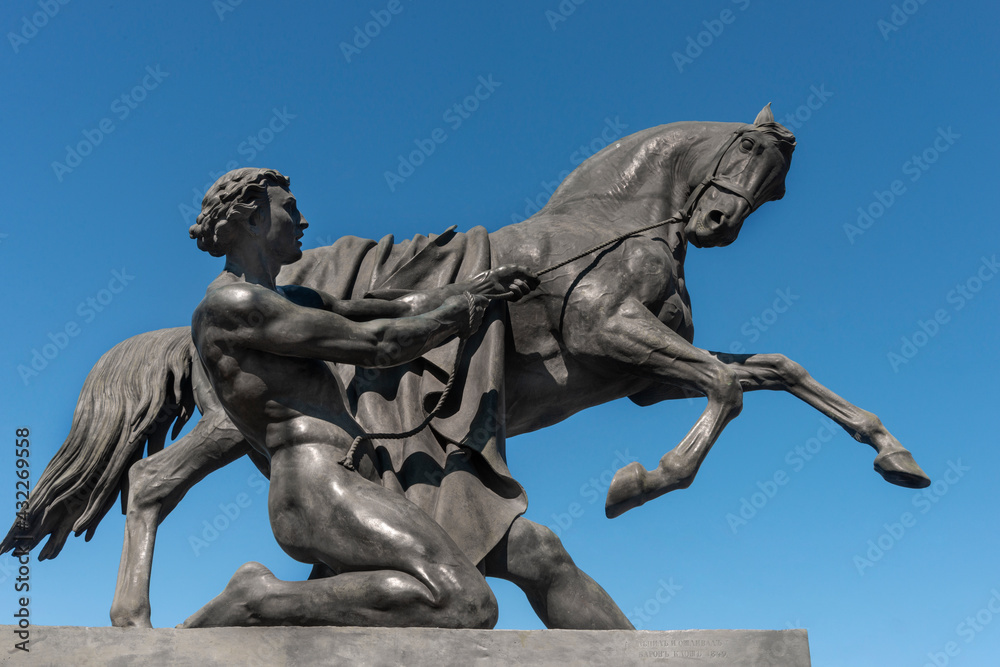Bronze sculpture of a horse  at an Anichkov bridge in St. Petersburg against the blue sky.