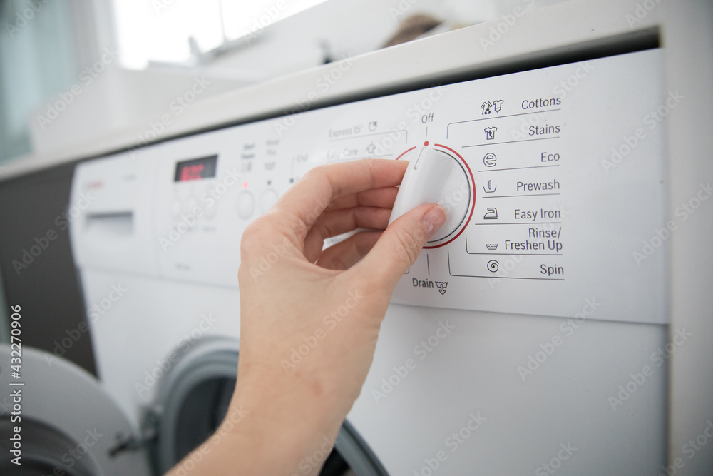 Caucasian female hand turning knob button washing machine white laundry chores domestic cleaning Caucasian female hand turning knob button washing machine white laundry chores domestic cleaning