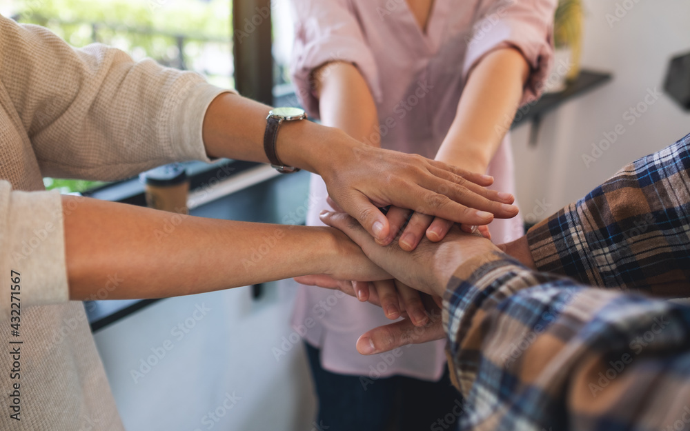 Closeup image of business team standing and joining their hands together in office