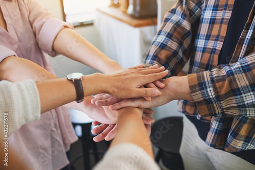 Closeup image of business team standing and joining their hands together in office