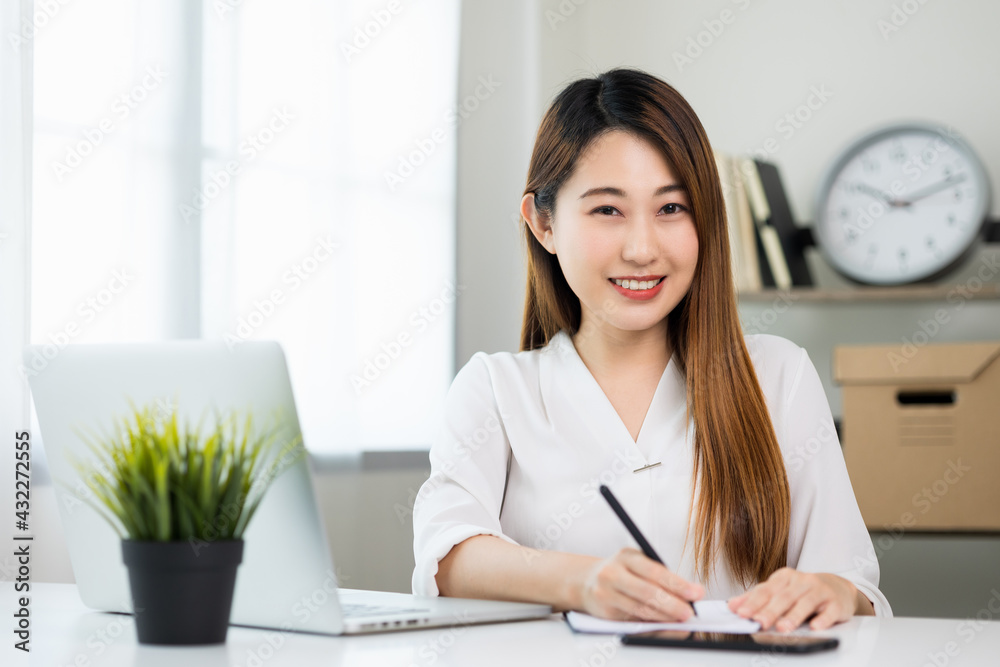Young asian beautiful business woman working with laptop sitting at home and note on book. Smiling charming happy young female doing homework meeting conference with team at home. Young asian beautiful business woman working with laptop sitting at home and note on book. Smiling charming happy young female doing homework meeting conference with team at home.