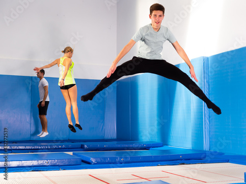 Smiling teenage boy jumping on trampoline in sports center. Youth sport lifestyle concept © JackF