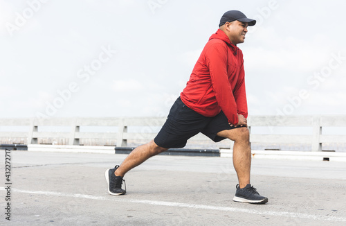 Young asian man wearing sportswear running outdoor. Portraits of Indian man stretching leg before running on the road. Training athlete work out at outdoor concept.
