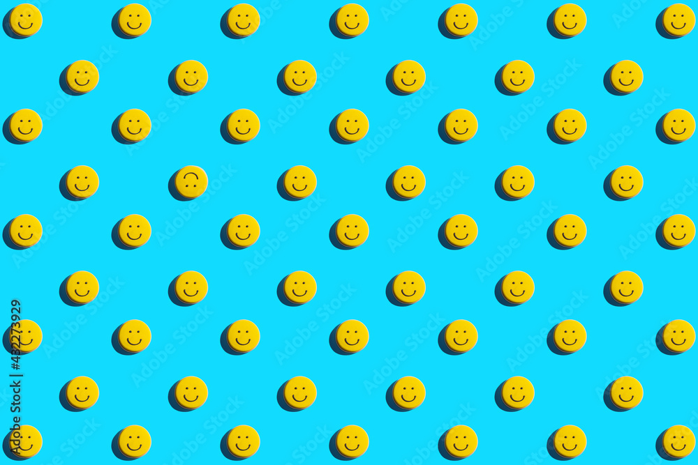 Yellow smiley face cookie, food, flat lay, top view, copy space on blue background. Be different.