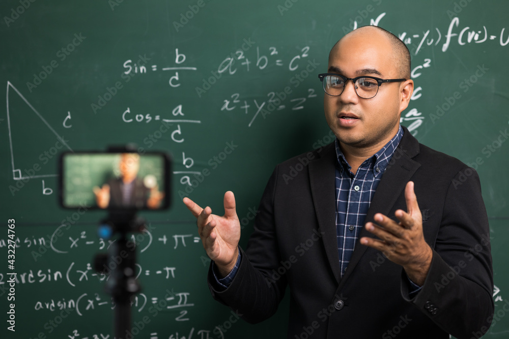 Indian young teacher man teaching online video conference live stream by smartphone. Asian teacher teaching mathematics class webinar online for students learning. Indian young teacher man teaching online video conference live stream by smartphone. Asian teacher teaching mathematics class webinar online for students learning.