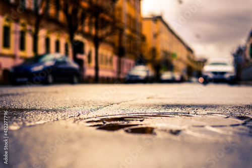 Rainy day in the big city  the street with parked cars. Close up view of a hatch at the level of the asphalt