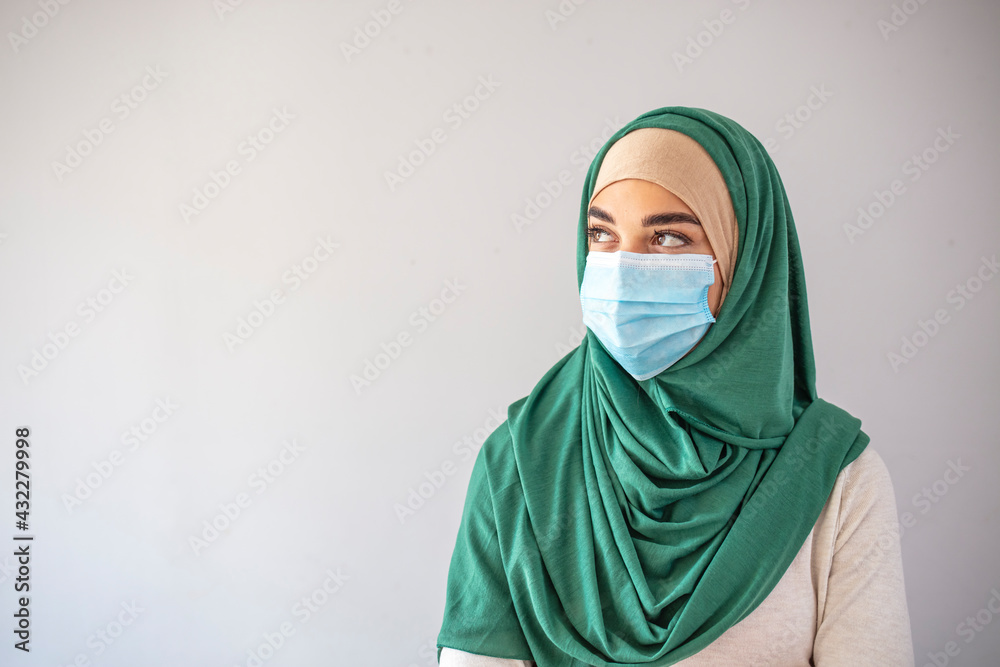 Muslim girl wearing surgical mask for protection. Hijab woman take a mask. Beautiful Arab young woman with disposable face mask. Protection versus viruses and infection. Muslim girl wearing surgical mask for protection. Hijab woman take a mask. Beautiful Arab young woman with disposable face mask. Protection versus viruses and infection.