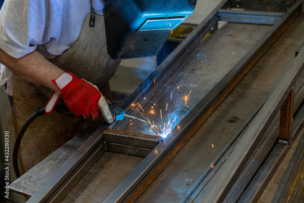 Man welding steel frames in a forgery and metal works workshop