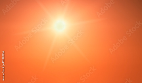 The sun shining brightly in a clear orange sky