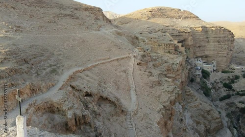 Aerial Panning Shot Of Religious Cross At Judaean Desert While Saint George Monastery In Background At Cliff - West Bank, Israel photo