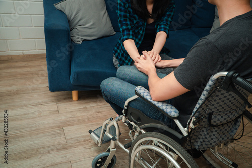 An asian man in a wheelchair in the home after a car accident and his wife to give encouragement. The concept of Mutual care and new technology has made people with disabilities Equality in society.