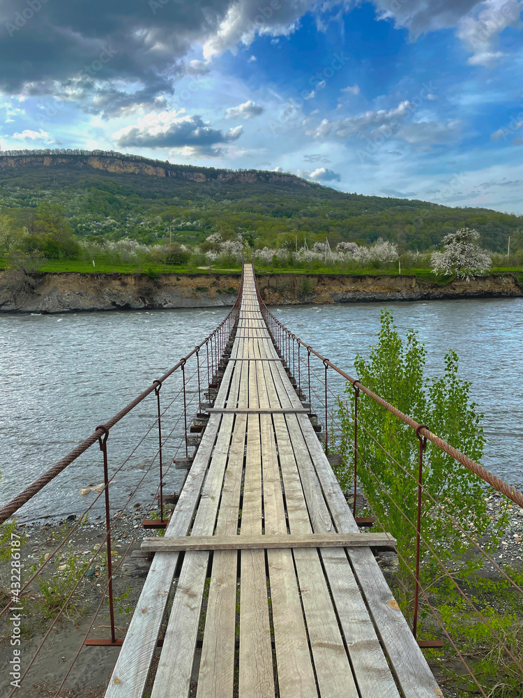Suspended pedestrian bridge over the mountain river