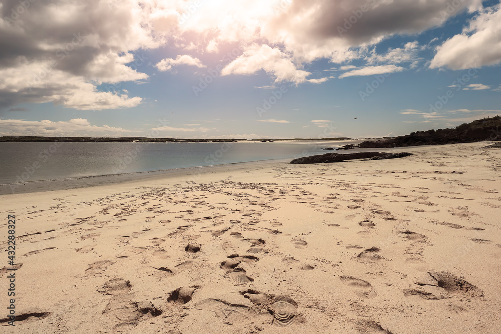 Obraz premium Tourist footprints on sand at Gurteen beach, county Galway, Ireland. Warm sunny day. Cloudy sky