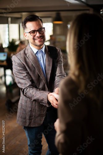 Businesswoman and businessman discussing work in office. Two friends handshake in office..